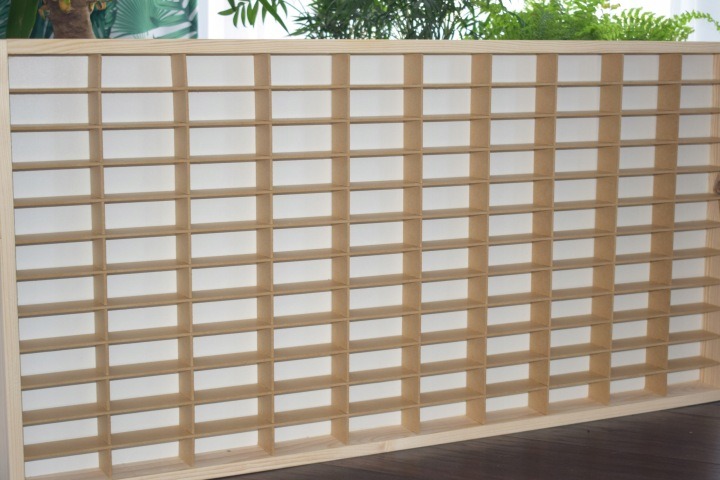 Béžová polica Dekoralove ponúka 80 priehradiek na modely autíčok. Má približne 79 × 40 cm, hĺbku 4 cm a vyberateľné prepážky z 3 mm HDF. Dodané závesy a skrutky slúžia na upevnenie na stenu; autíčka nie sú súčasťou balenia.